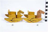 S2003-589.42,43.jpg; S2003-0589; Poppenhuistoebehoren bestaande uit twee kinderstoelen, kast, twee dressoirs, aanrecht, vleugel, klok, twee planten, fornuis, drie pannen, vijf tafels, zes eettafel stoelen, zitbank, twee stoelen, twee hobbelpaarden, radio, lamp, bed met beddengoed, toilet, servies en zeven poppen; kinderstoel